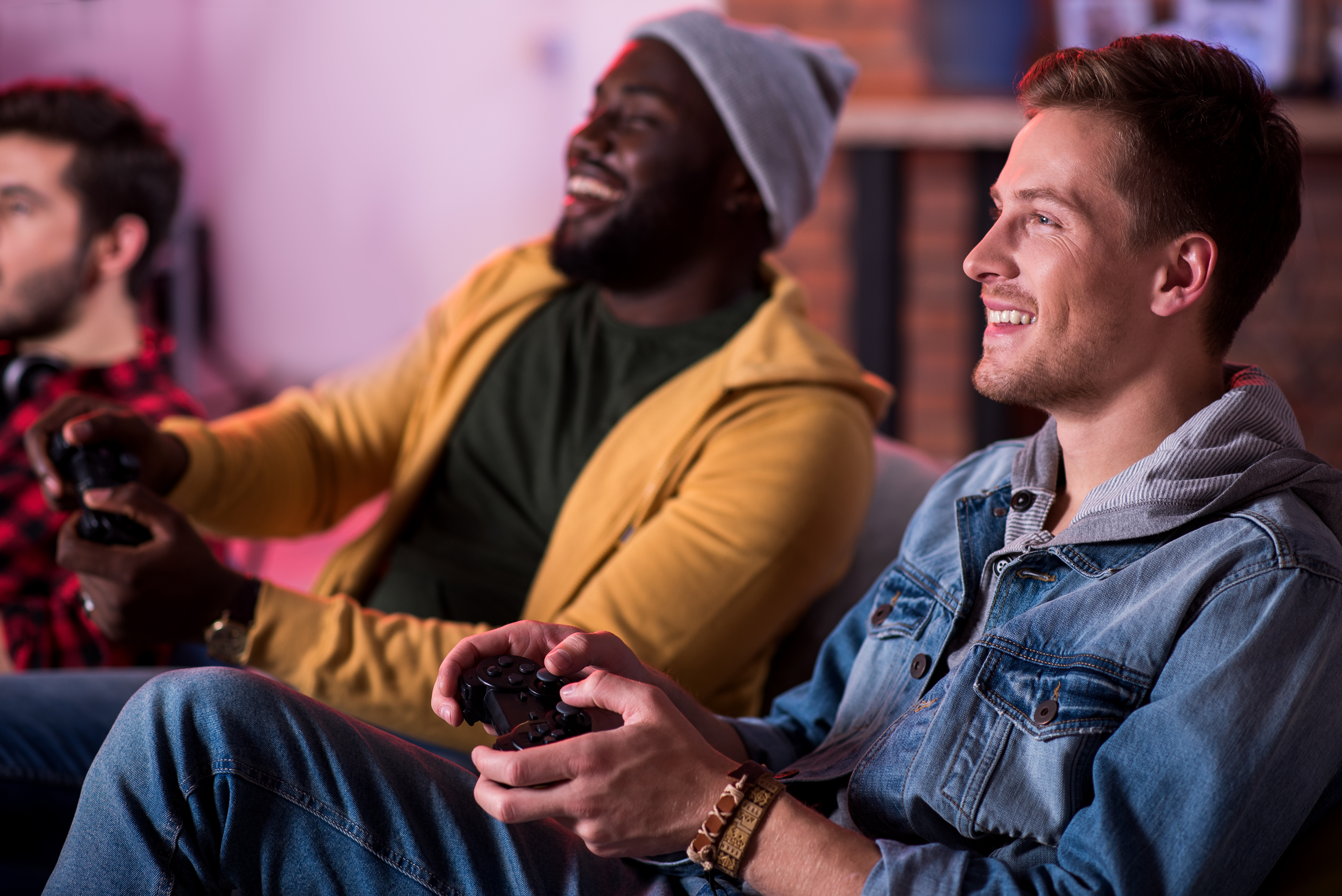 Two men in their twenties laughing and playing on a games console